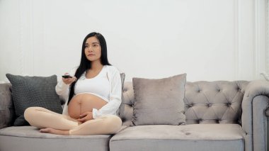 Hamile genç izlerken televizyon ve değişim ile kanal uzak