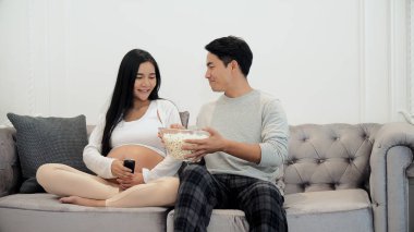 Young couple enjoy to watching television and use remote control clipart