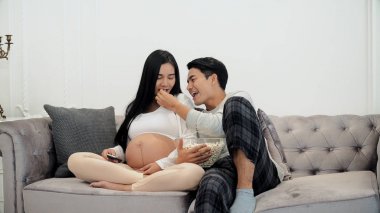 Young couple enjoy to watching television and use remote control clipart