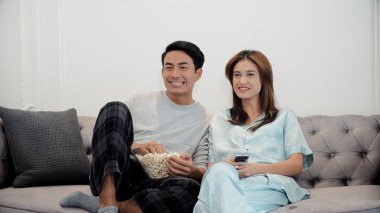 Genç çift televizyon izlerken zevk ve Uzaktan kumandayı kullanın