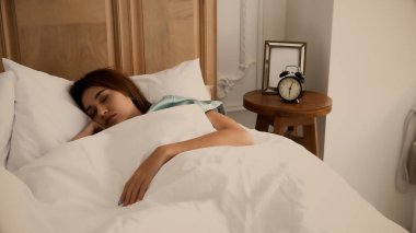 Genç ve güzel bir kadın yatakta uyuyor.