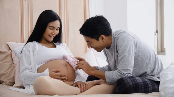 Joven marido jugando pequeños zapatos en el vientre esposa embarazada —  Fotos de Stock