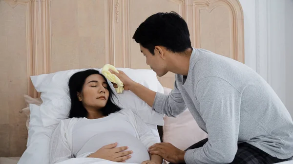 Joven hombre utiliza toalla limpiar la cara esposa para reducir la fiebre —  Fotos de Stock