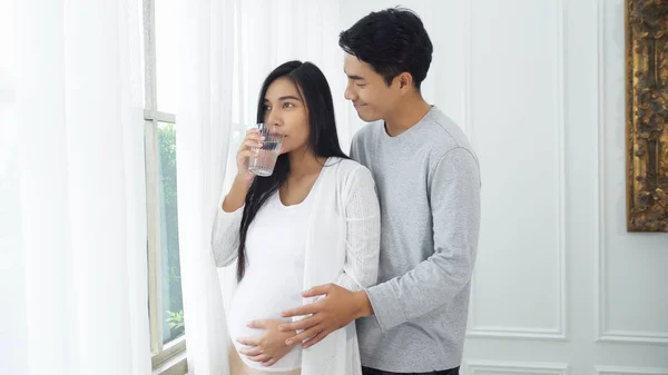 Joven marido cuidar a su esposa embarazada con agua de bebida —  Fotos de Stock