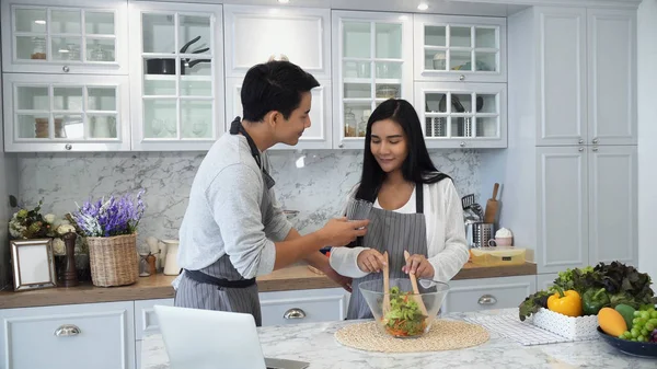 Los esposos jóvenes que cocinan juntos en la cocina —  Fotos de Stock