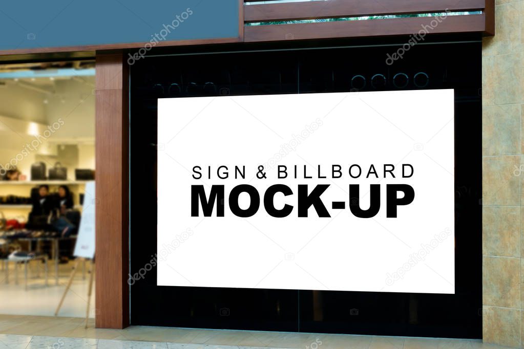 Mock up large blank billboard on the wall near entrance of fashion shop with clipping path, Empty signboard for information or promotion advertising at shop, blurred people in background