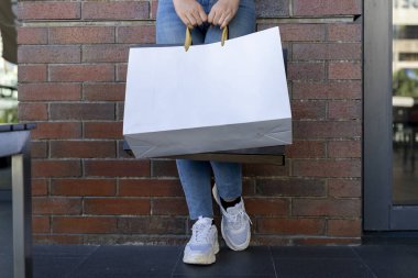 İki çanta tutan genç bir kadın, kırpma yolu olan boş bir ekran poşeti, logo ya da grafik eklemek için alışveriş torbasında boş alan.