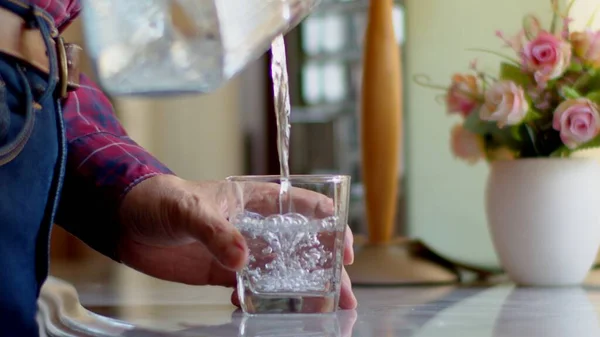 close up shot, man pouring water into a water glass.