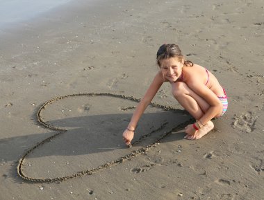 güzel gülümseyen kız birçok kupa sahilde çizer.