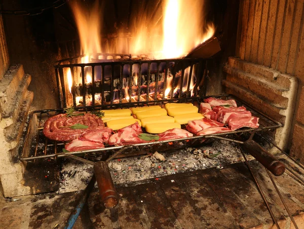 Cozinhar carne crua na lareira com um fogo quente aceso — Fotografia de Stock