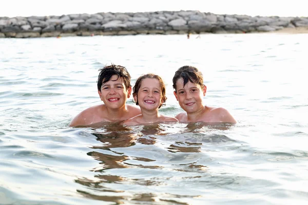 Três irmãos amigáveis nadando no mar durante as férias de verão — Fotografia de Stock