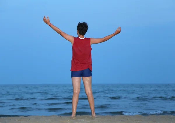 Chłopiec z podniesionymi rękami, nad brzegiem morza o zmierzchu — Zdjęcie stockowe