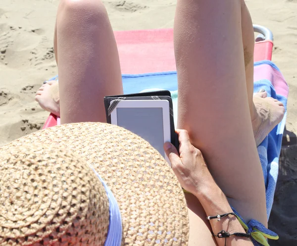 Giovane donna con cappello e gambe lunghe durante la lettura di una tecnologia — Foto Stock