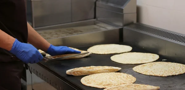 Ervaren kok met latex handschoenen koken brood op de hete plat — Stockfoto