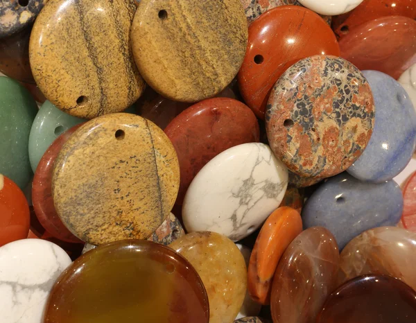 Satılık bir kolye eklemek için delik ile sert yontulmuş taşlar — Stok fotoğraf