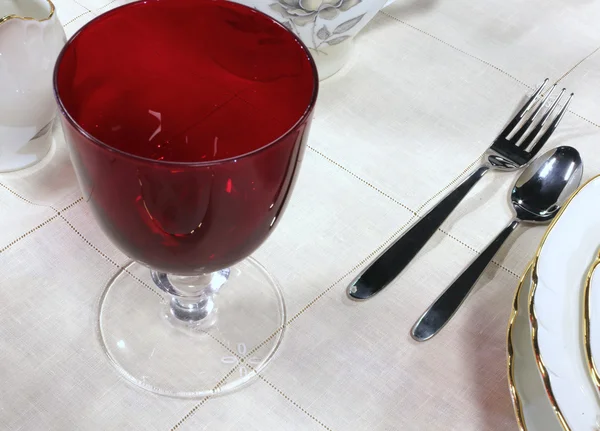 Vetro cristallo rosso con forchetta e cucchiaio sul tavolo — Foto Stock