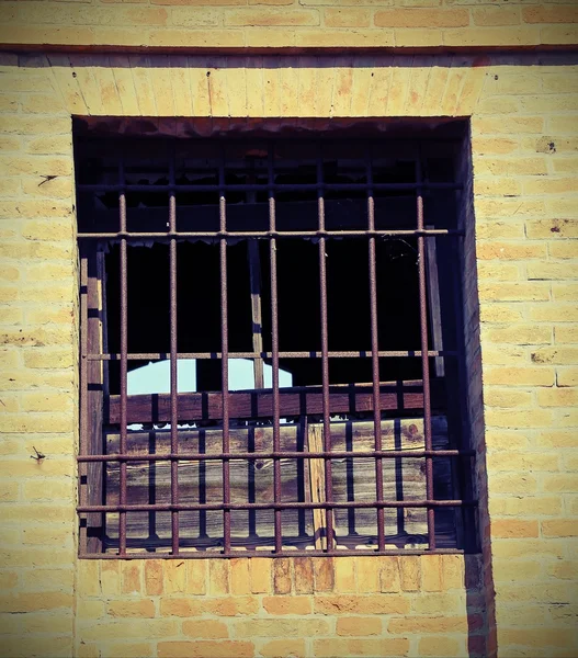 Broken window of an abandoned house with iron bars a — Stock Photo, Image