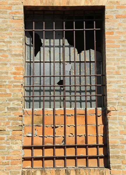 Разбитое окно заброшенного дома с железными решетками — стоковое фото