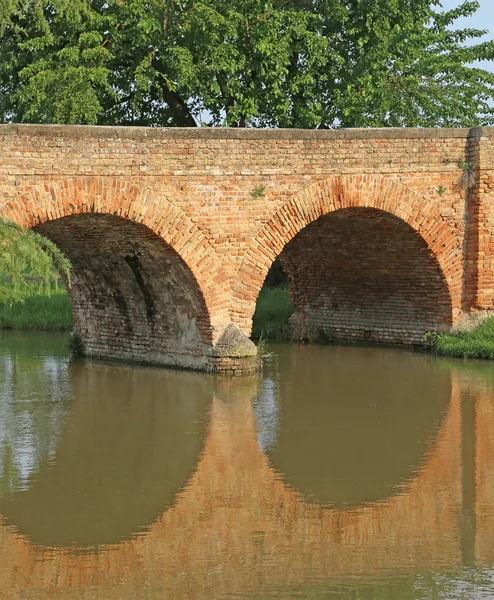 Ancient bridge made of red brick on the river in Europe — Stock Photo, Image