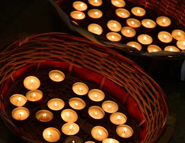Mnoho svíčky zapálil v proutěném koši — Stock fotografie