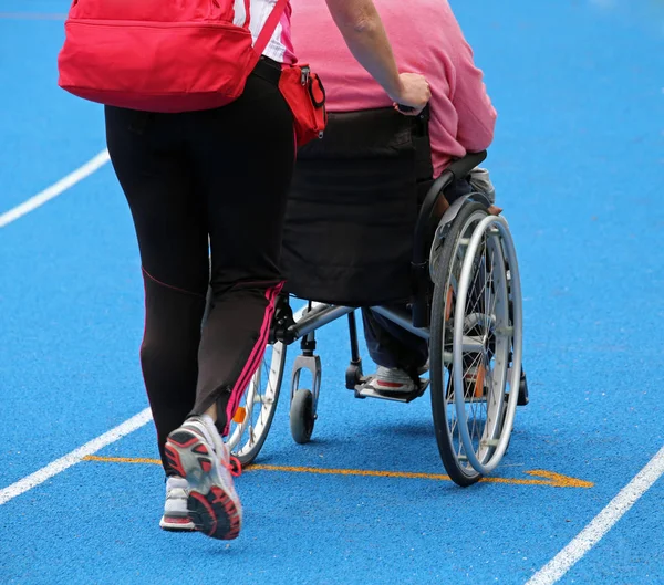 Tekerlekli sandalye ile bir görevli sp sırasında atletik yolda — Stok fotoğraf