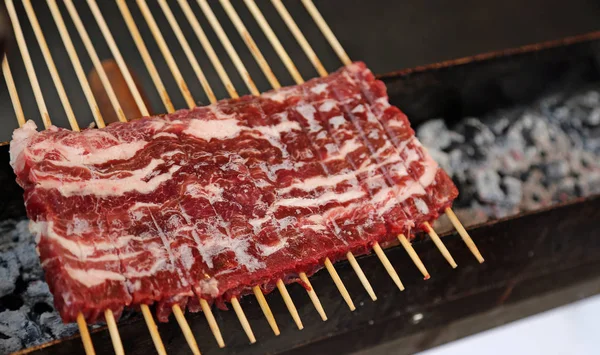 Rood rauw vlees tijdens het koken op de brazier in een straat kraam — Stockfoto
