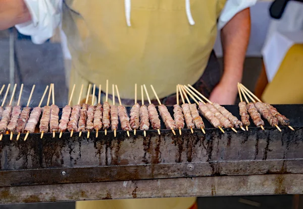 Уличный повар готовит сырое красное мясо на гриле — стоковое фото