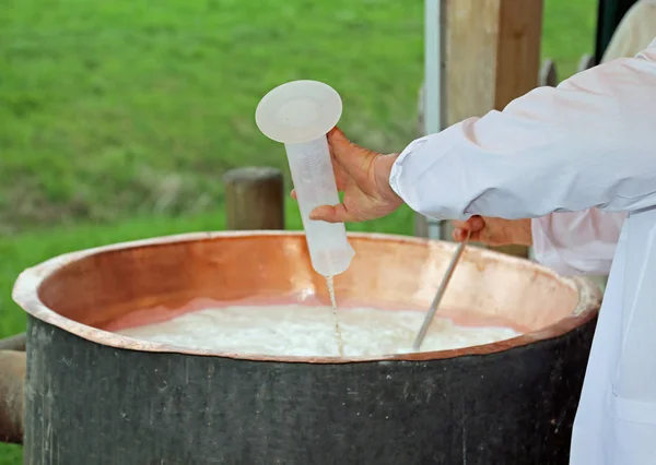 Cook pours rennet into the warm copper cauldron to produce chees — Stock Photo, Image