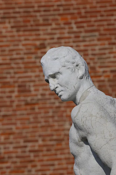 Estátua de um personagem pensador com o tijolo no fundo — Fotografia de Stock