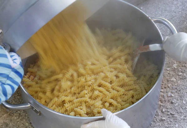 Cocinero vierte la pasta en la olla grande en el restaurante — Foto de Stock