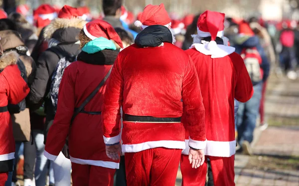 Ludzie z czerwone ubrania Mikołaja spaceru w parku publicznego o — Zdjęcie stockowe