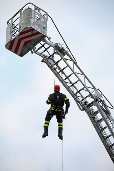 Escalador de bombeiros com capacete vermelho cai da escada tr — Fotografia de Stock