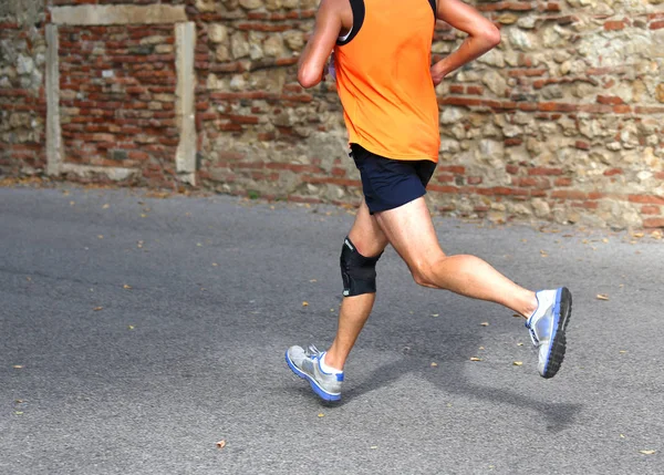 Corredor corriendo rápido con una rodillera para apoyar el ligamento muscular — Foto de Stock