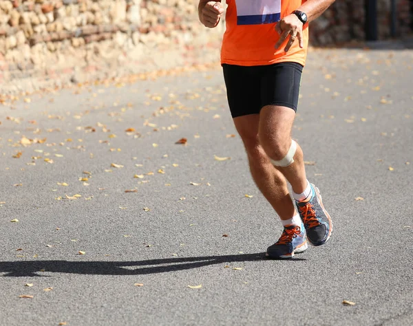 Corredor corre com sportswear e um patch perto do joelho — Fotografia de Stock