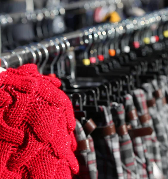 Red sweater wool and many winter clothes on hangers — Stock Photo, Image