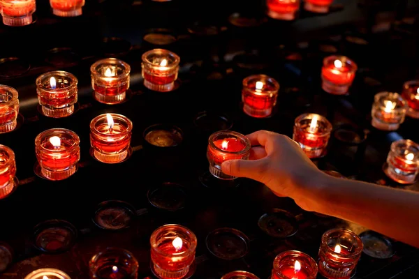 Young girl lights a red candle in church and then she says a pra — Stock Photo, Image