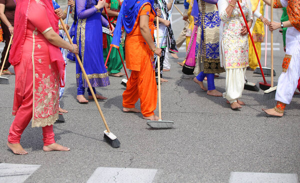 barefoot women of Sikh Religion sweep the road during the celebr