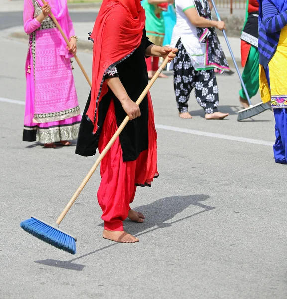 Багато босоніж жінки з барвистим одягом розмотують мощену дорогу — стокове фото