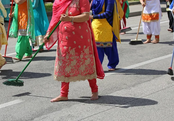 Босоніж жінки з барвистим одягом розчісують асфальтовий дорожній дурі — стокове фото