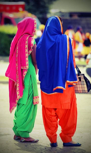 Дві жінки з різнокольоровим одягом відвідують захід — стокове фото