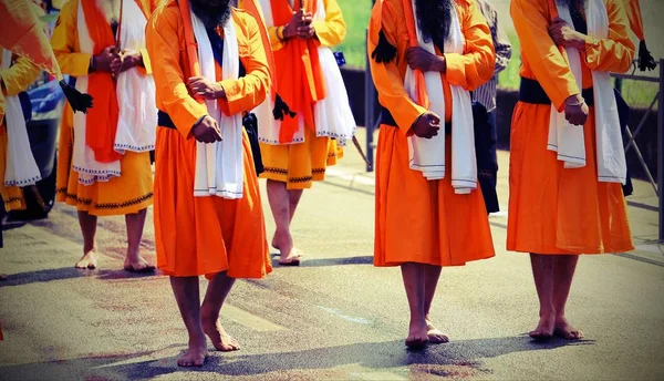 Men of Sikh Religion with long orange clothes walk barefoot with — Stock Photo, Image