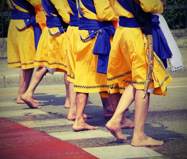 Five men of Sikh Religion with long dresses walking barefoot