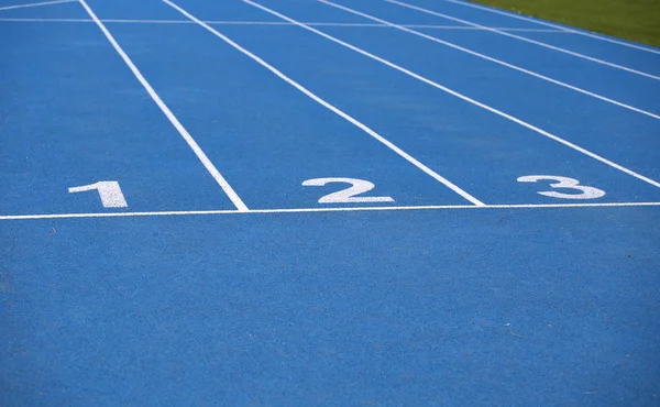 Corsie di una pista atletica blu con uno due e tre numeri — Foto Stock