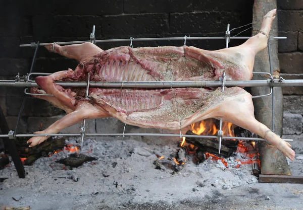 Pig on the spit and slowly cooked on the large fireplace during — Stock Photo, Image