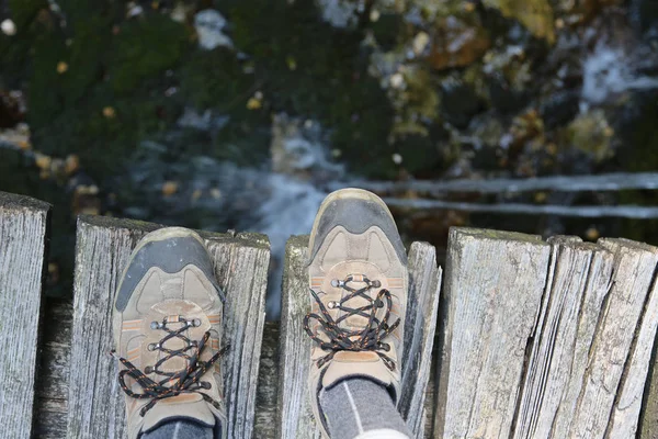 Hiking shoes of a hiker on the wooden bridge — Stock fotografie
