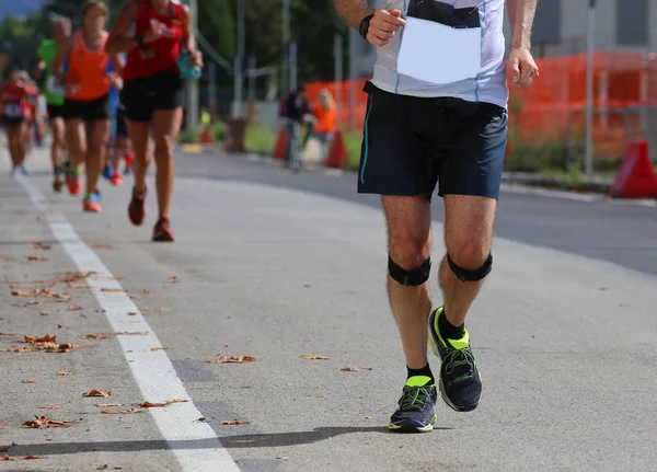 Corredor atlético con banda elástica en la rodilla corriendo rápido durin — Foto de Stock