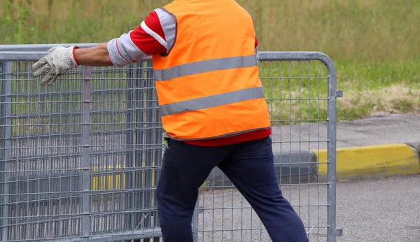 Εργαζόμενος με πορτοκαλί γιλέκο υψηλής ορατότητας, ενώ κινείται το φράχτες — Φωτογραφία Αρχείου