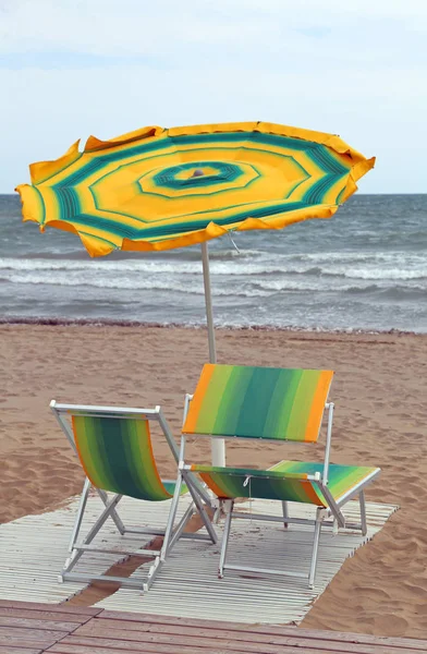 Mar agitado y la playa con una sombrilla en el viento con dos de —  Fotos de Stock