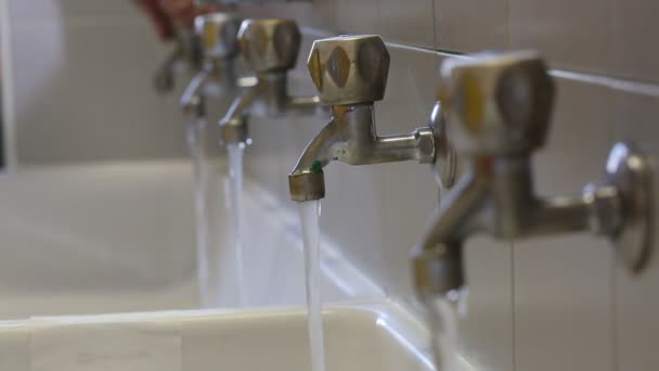 La mano cierra el agua a muchos grifos en el baño para evitar desperdiciar — Vídeos de Stock