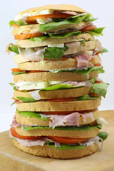 Bir kesme tahtası ve beyaz peynir jambon domates ile büyük sandviç — Stok fotoğraf